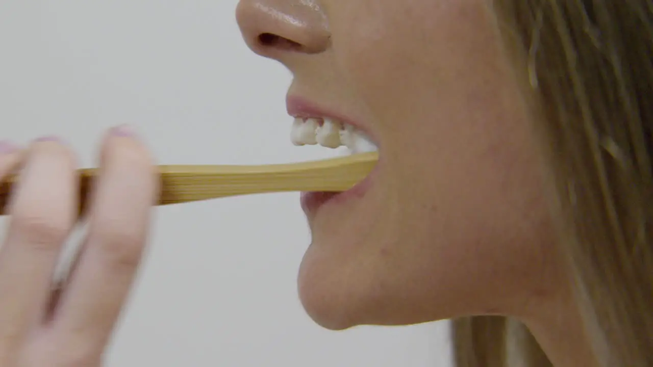 A woman brushing teeth turning towards camera