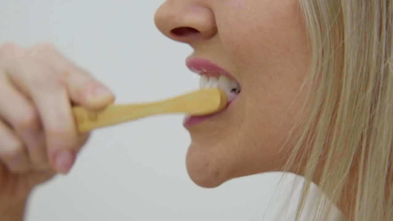 A light skinned woman brushing teeth close up