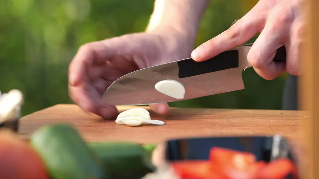 a young man cutting garlic on a wooden board in his garden close up