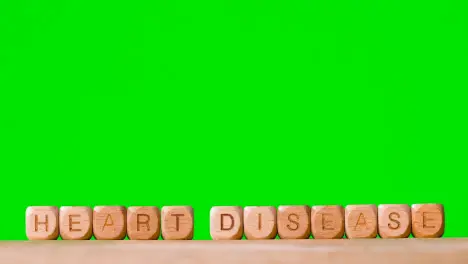 Medical Concept With Wooden Letter Cubes Or Dice Spelling Heart Disease Against Green Screen