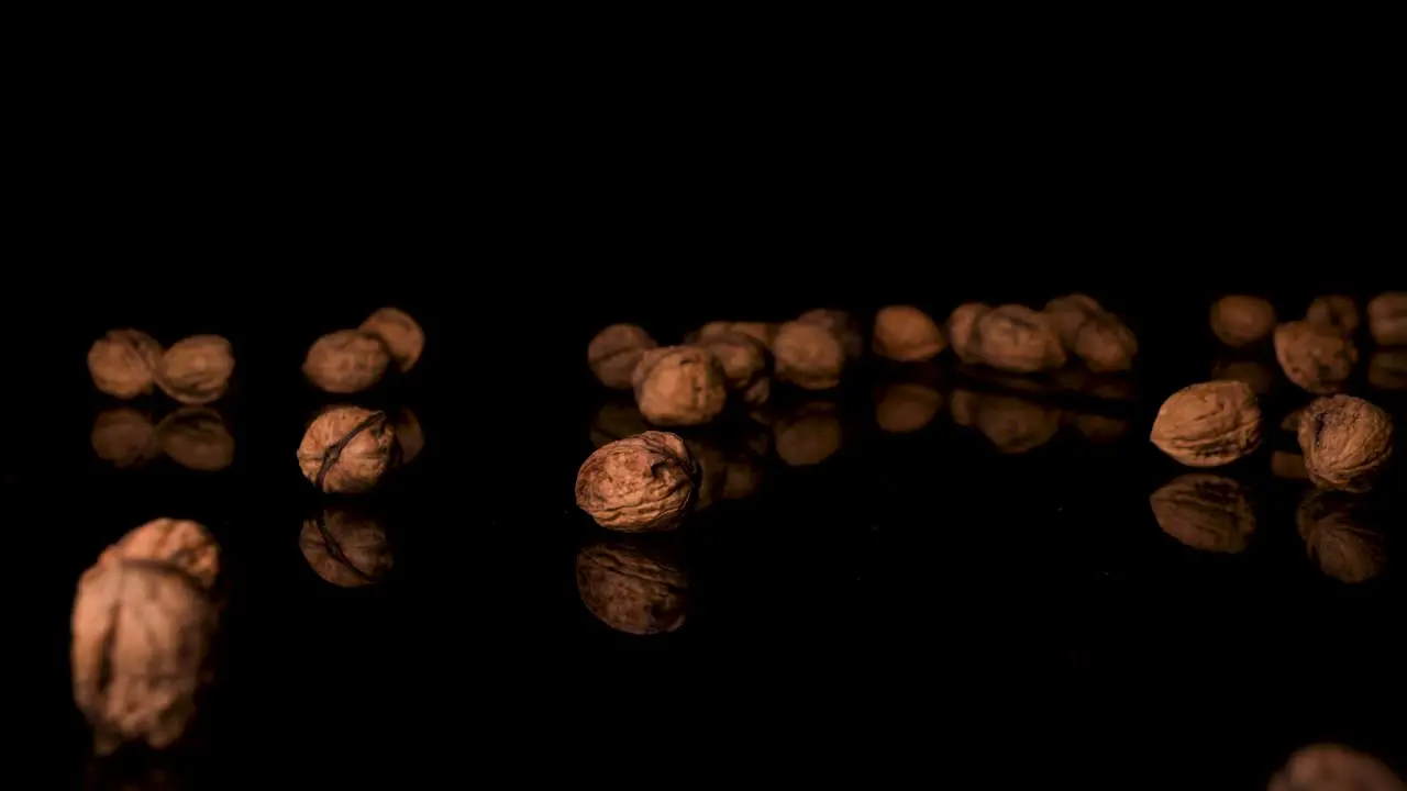 Vegan-Approved Organic Walnuts Falling onto Glassy Black Surface