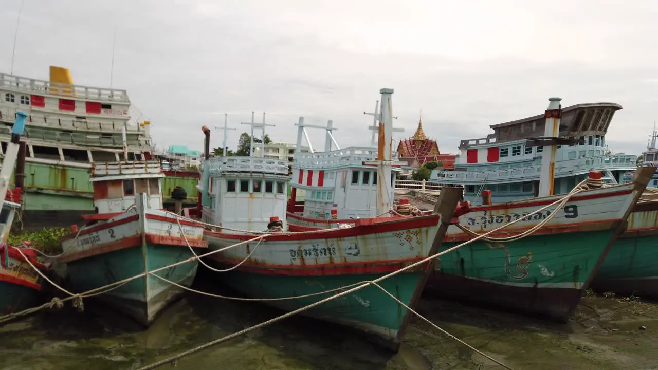 Fishing Boats moored in the mud at a river bank during the low tide in Samut Sakhon Thailand and waiting to be deployed again