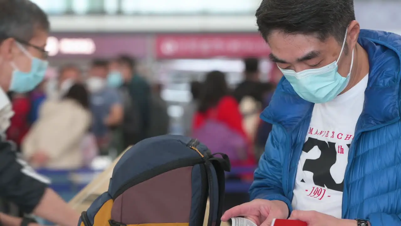 A flight travel passenger manages his airline boarding pass after checking in at the airline desk counter at Hong Kong International Airport