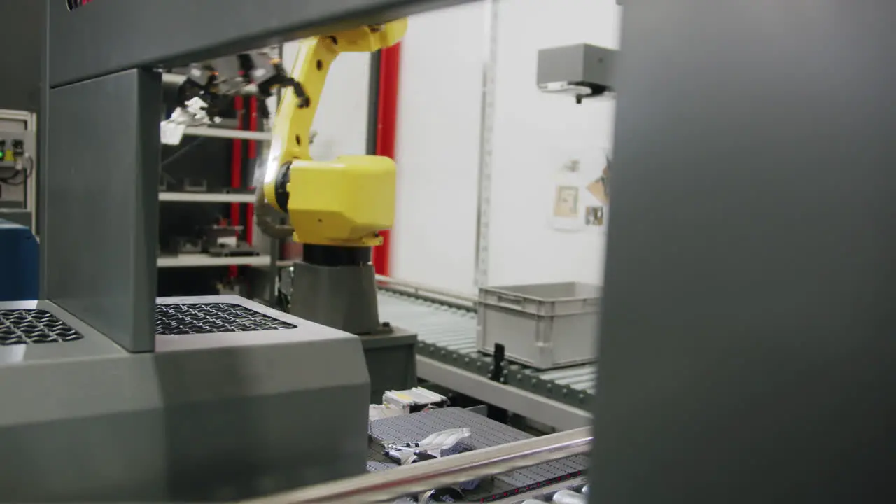 An industrial robotic arm takes a car part from the conveyor belt and transfers it to the next step in the factory process