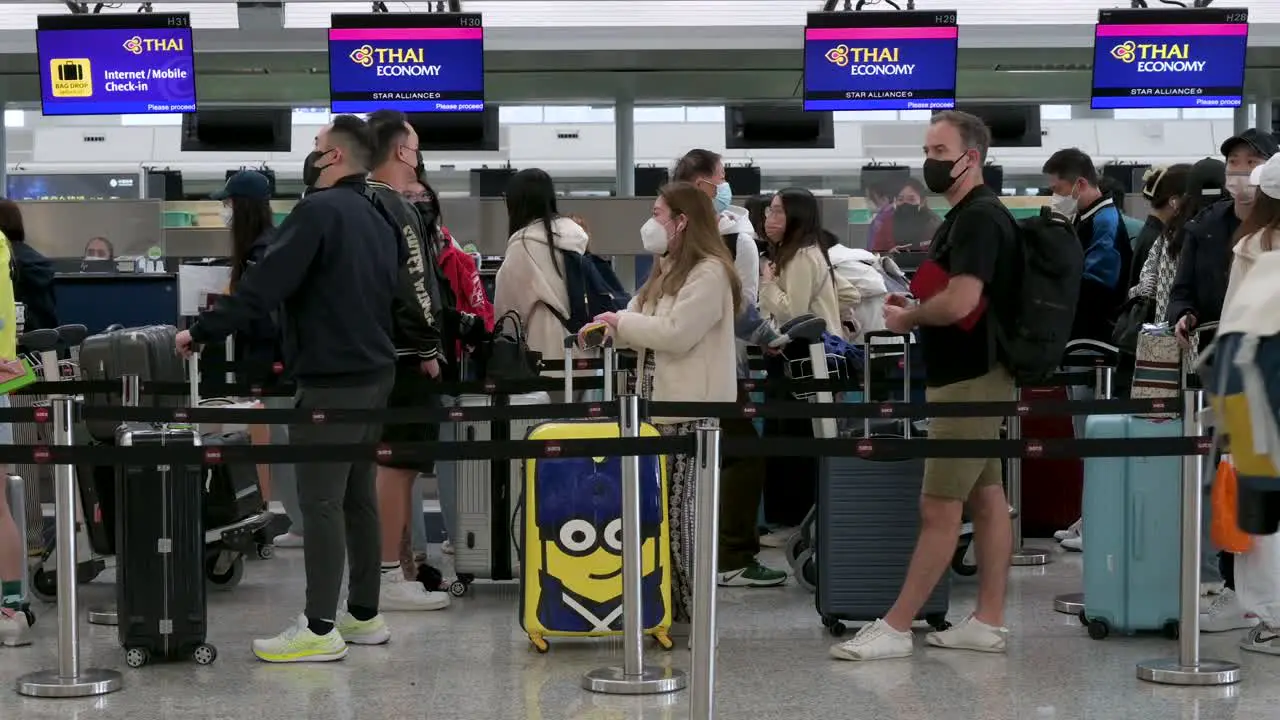 Travel passengers queue in line to check in at the flag carrier airline of Thailand Thai Airways desk counter at Hong Kong International Airport