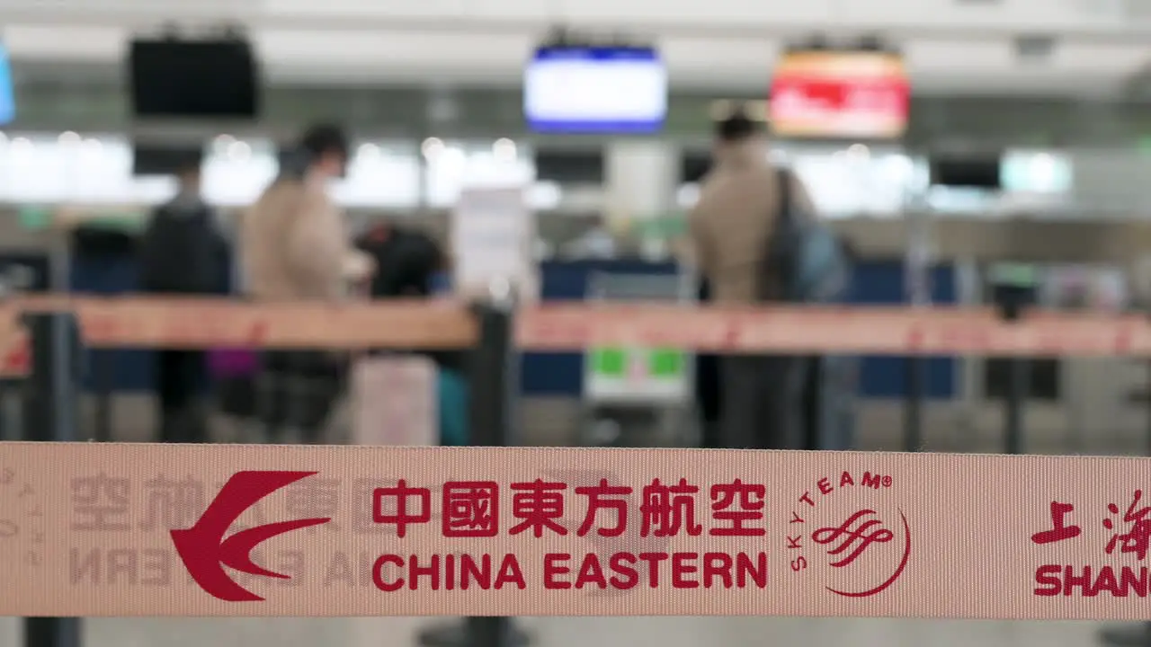 Chinese flag carrier China Eastern airline logo is seen on a queue belt in the foreground at a check-in desk counter at the Chek Lap Kok International Airport in Hong Kong