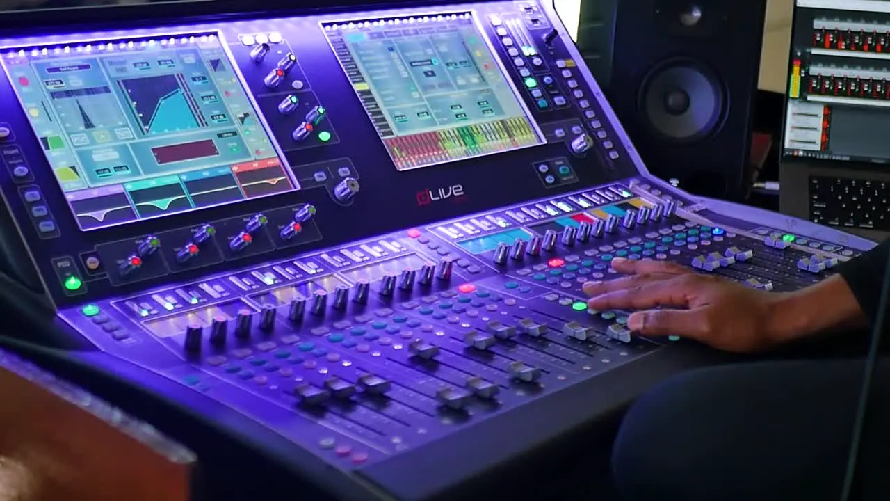 A medium shot capturing a hand operating an audio mixer skillfully adjusting knobs and sliders