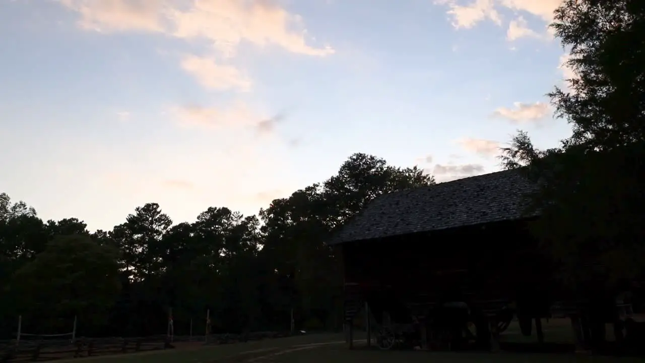 Time lapse of the sun setting over a cotton mill at a farm