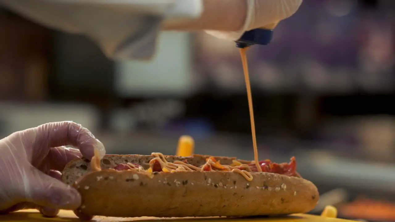 Chipotle sauce being poured over a sandwich bread roll in a deli slow motion shot