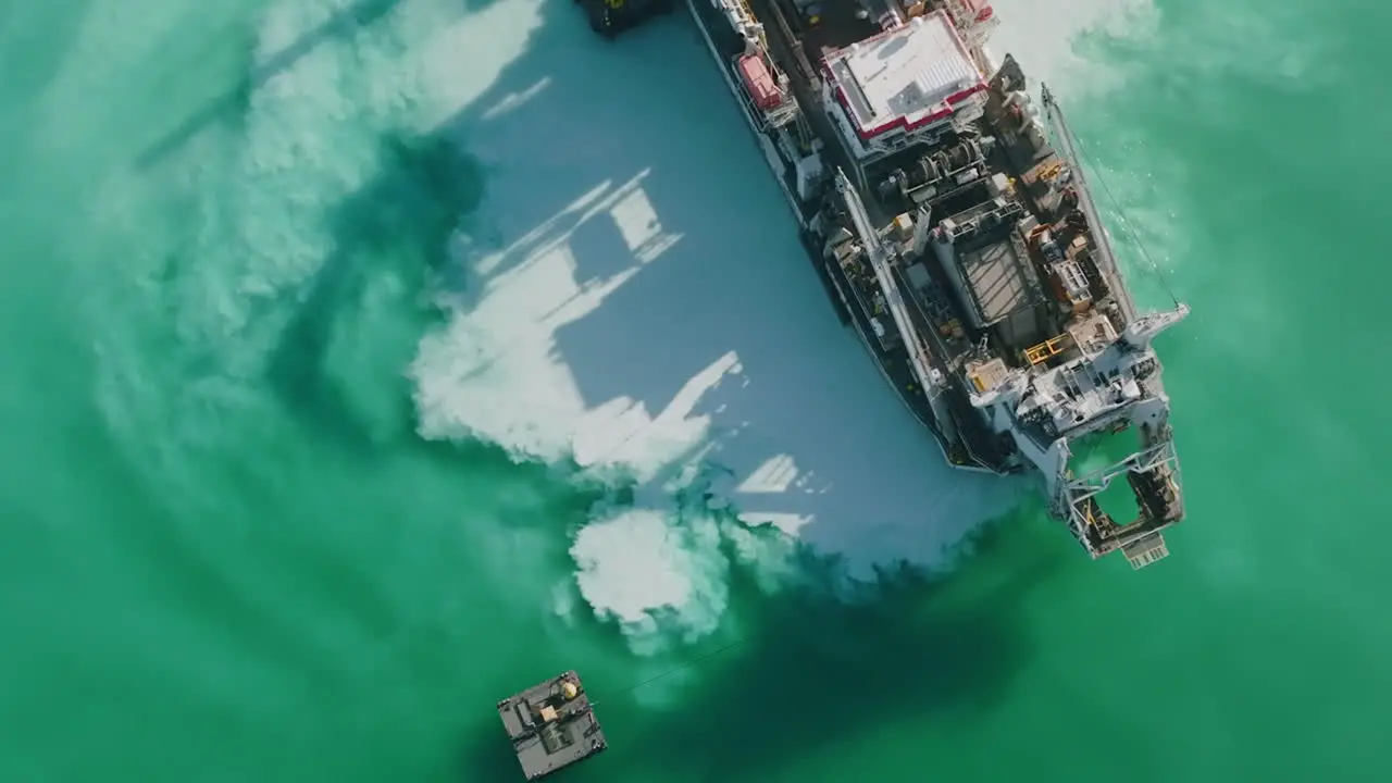 Close up aerial footage of the clouds of sand and dust in the water off of a sand dredging ship