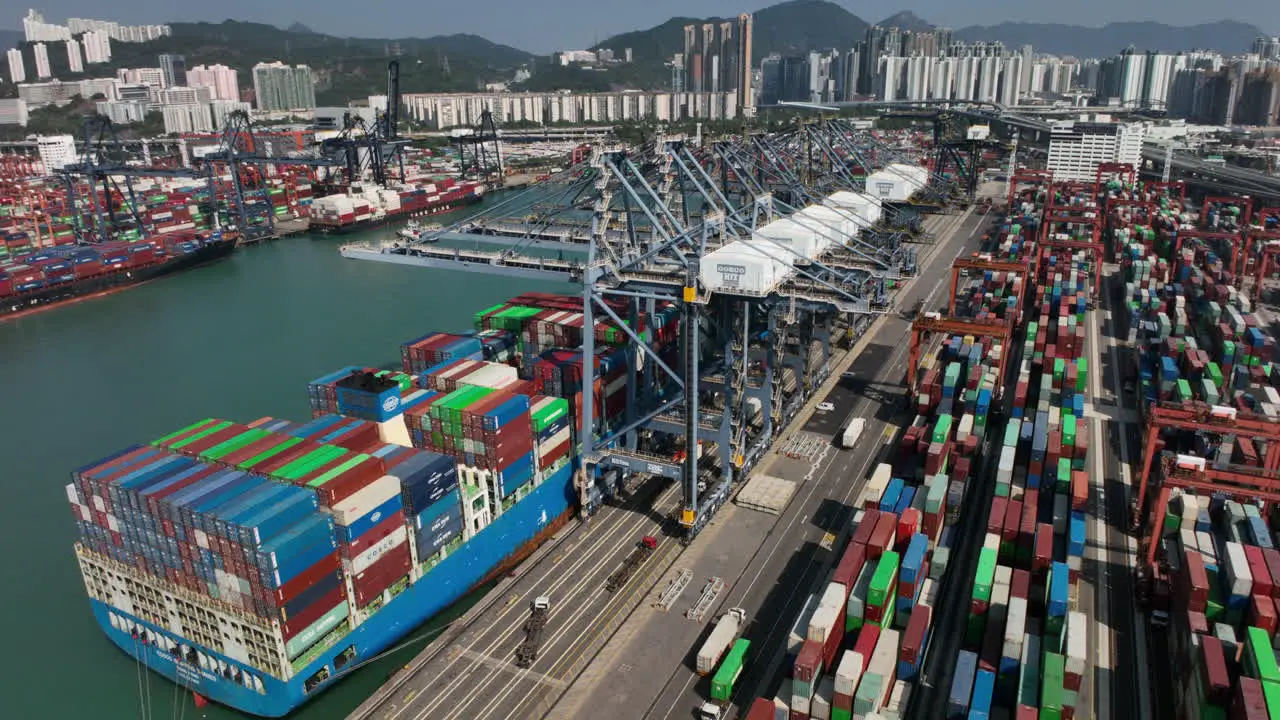 Aerial Shot of Crane Loading Huge Container Ship in Hong Kong Harbour Port on a Sunny Day