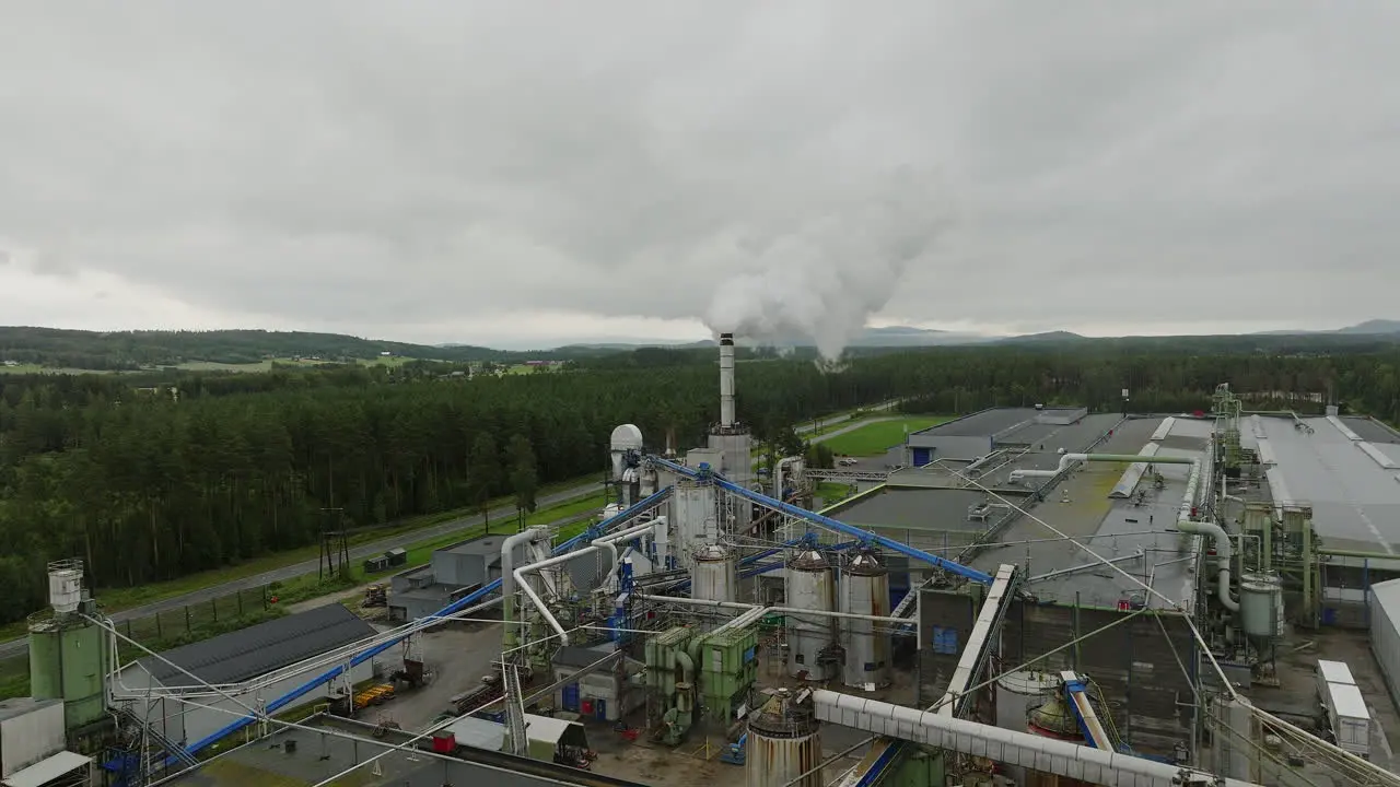 Lumber mill with piles of saw dust emitting gases from smokestack aerial