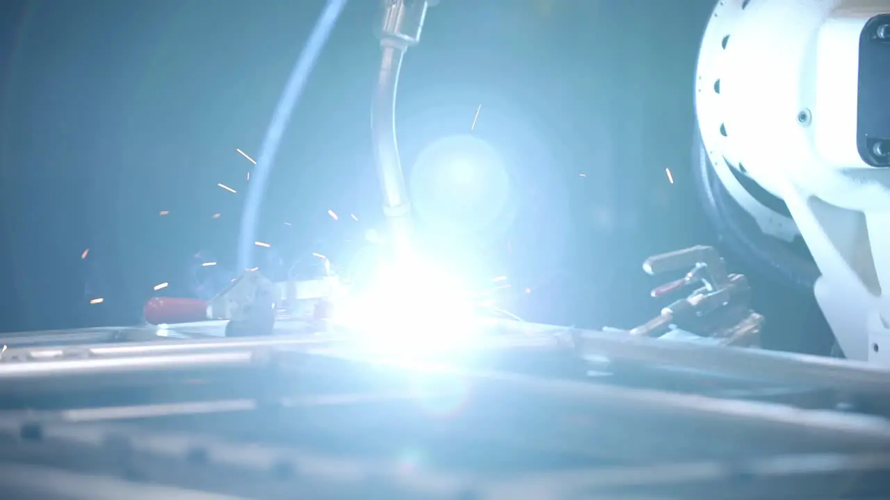 Close slow motion footage of a robotic welder making welds on a steel frame