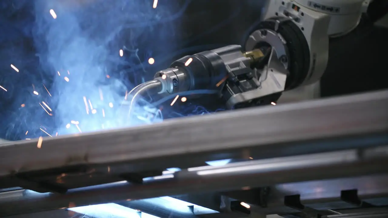 Slow motion footage from the ground of a robotic welder putting in a weld on a steel frame