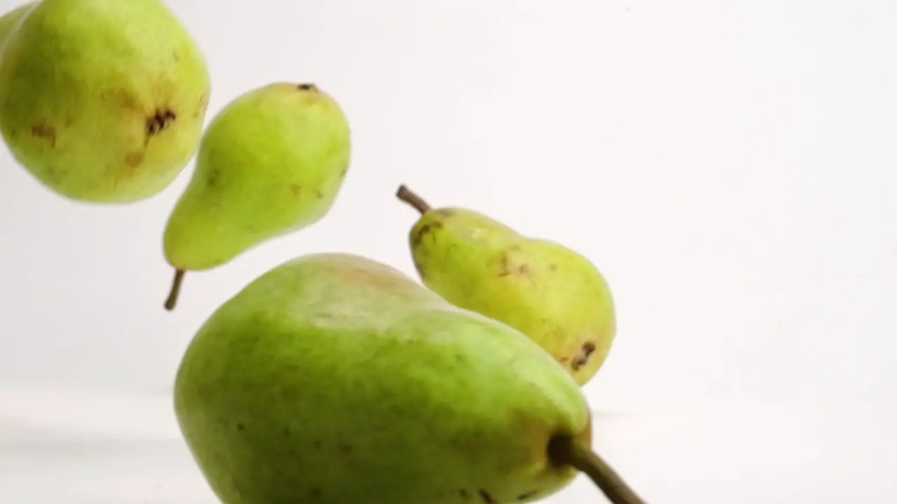 Whole pears bouncing in slow motion on white studio backdrop in 4k