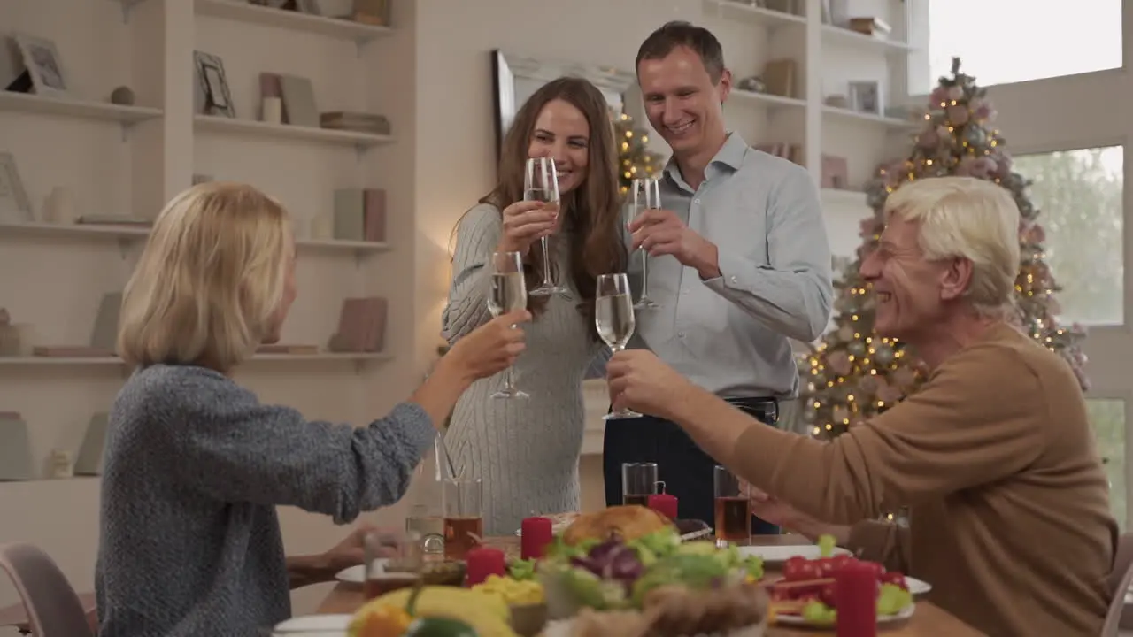 Young Adults And Their Elderly Parents Toasting And Celebrating Christmas Dinner At Home