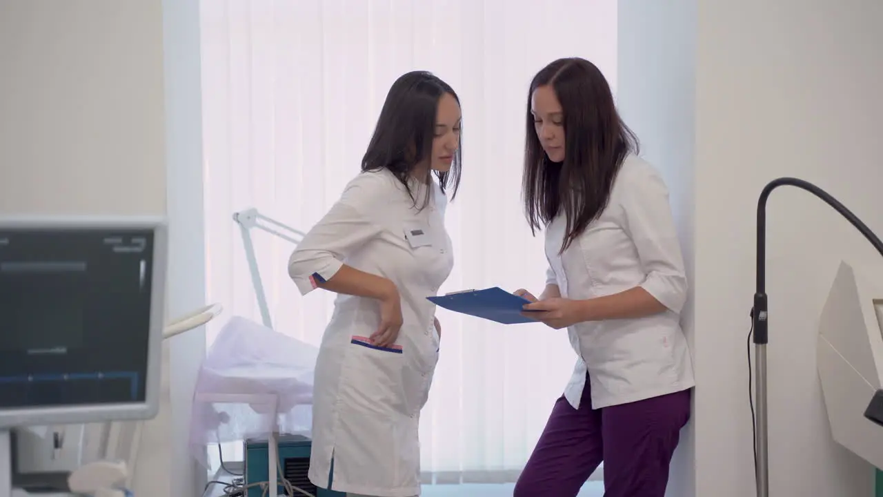 Female Doctor And Nurse With A Clipboard Talking About Medical Diagnosis And Treatment In The Hospital