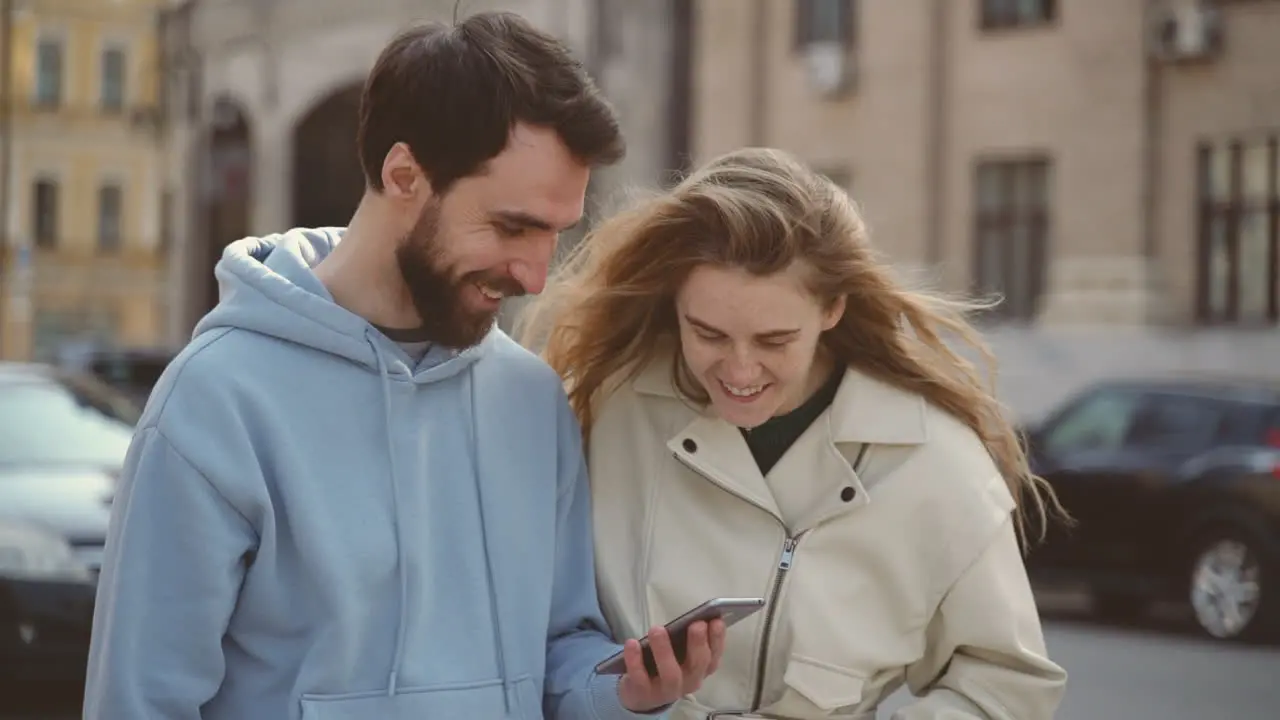 A Young Couple Watching Something Funny On The Screen Of The Cell Phone