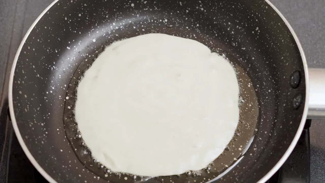 Close-up shot wet pancake batter being poured into a metal pan with Oil Top View