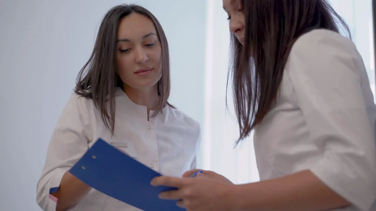 Female Doctor And Nurse With A Clipboard Talking About Medical Diagnosis And Treatment In The Hospital 1