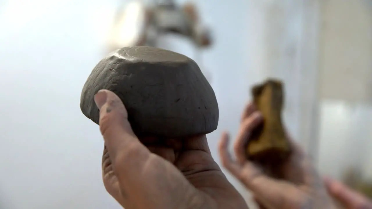 Smoothing out a handmade clay bowl with a sponge in a ceramics workshop Handheld close up shot