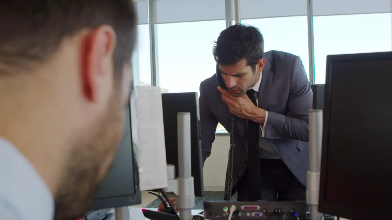 Businessman Making Phone Call Standing At Desk In Office