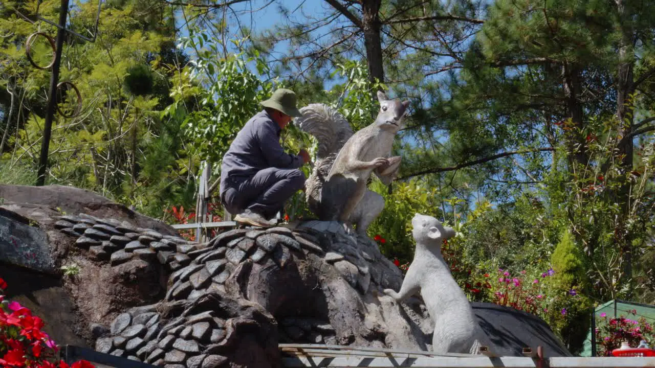 A man is carefully painting a squirrel statue at Da Lat Sculpture Museum in Vietnam