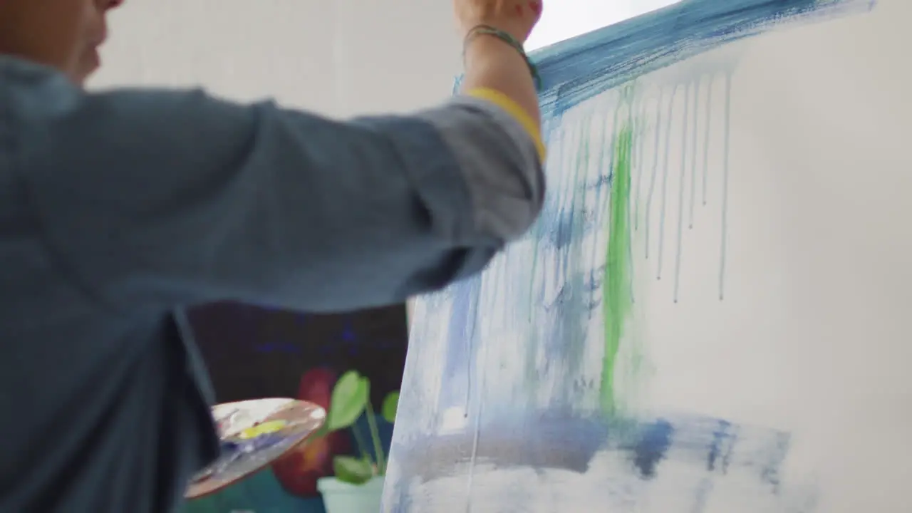 Artist paints on a canvas in a bright studio