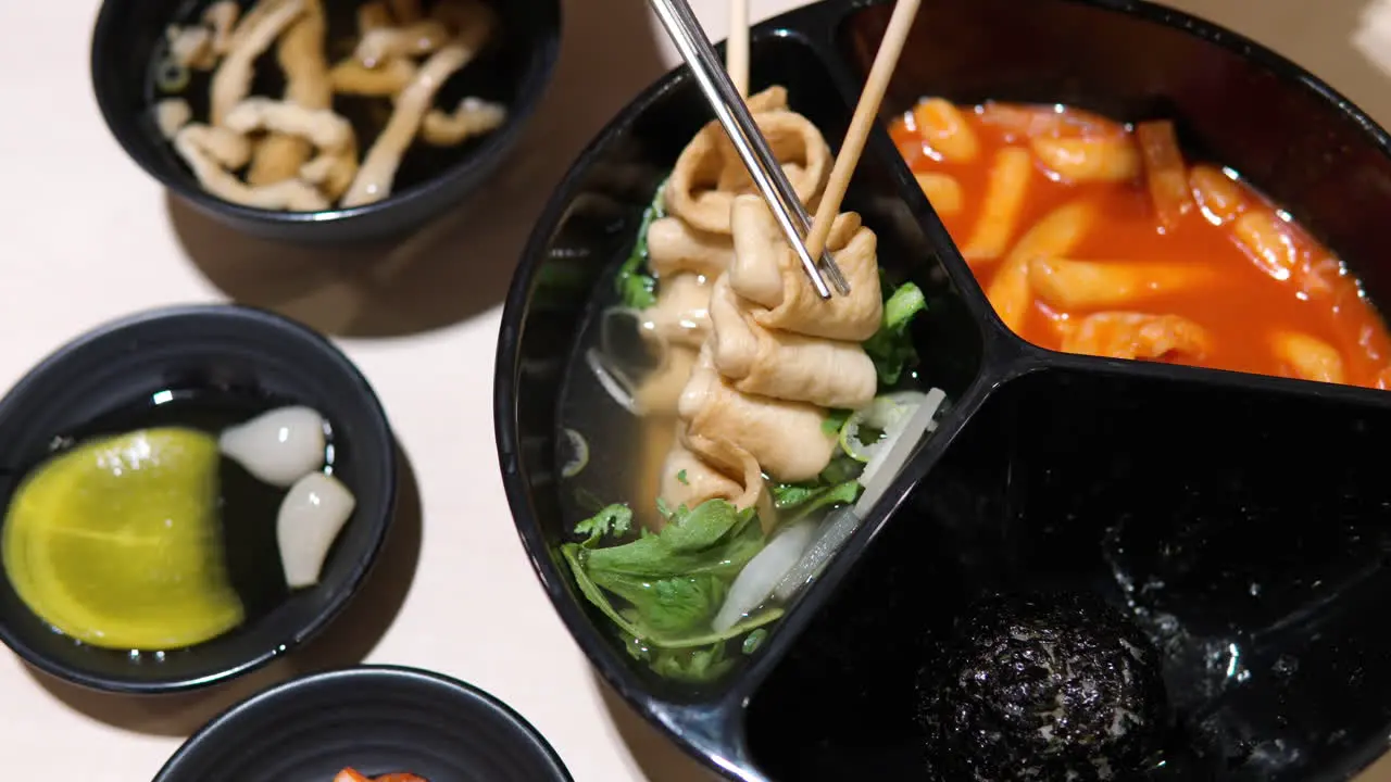 Woman takes Korean Odeng or Fishcake off Wooden Skewer