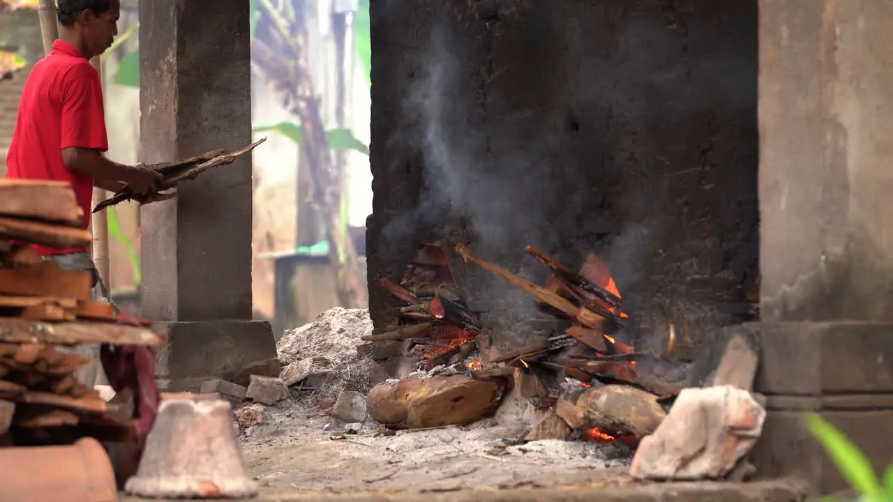 a middle-aged man is adding fuel to burn pottery or clay ceramics to make the product stronger