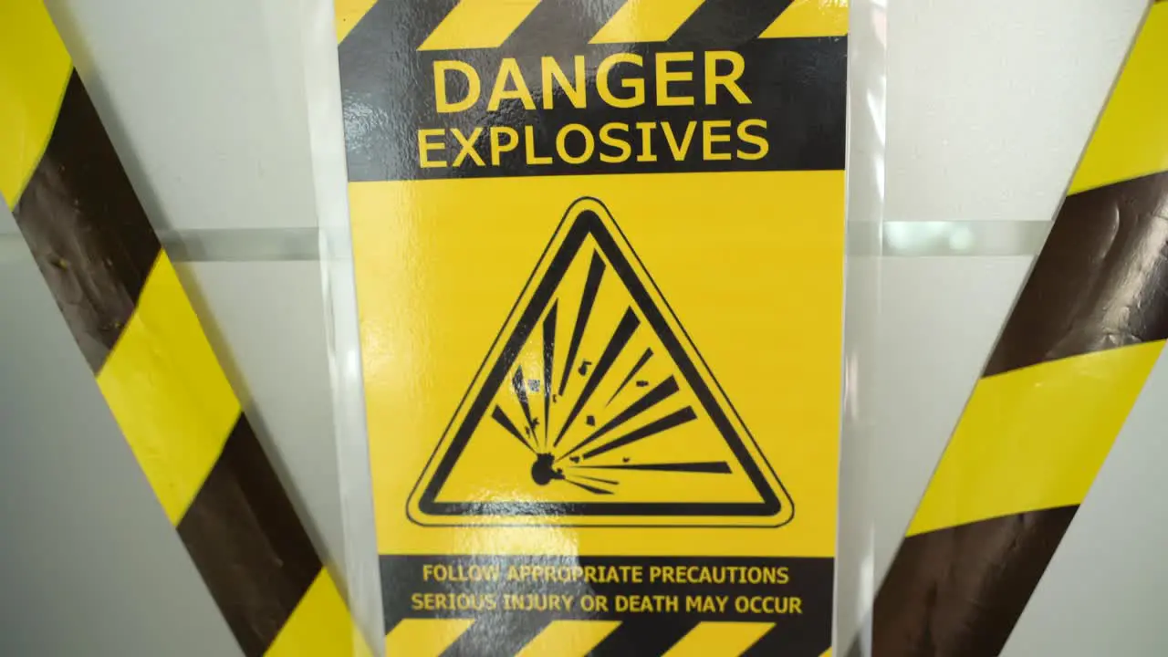 Danger hazard explosion warning safety sign with yellow precaution ribbon hanging on door