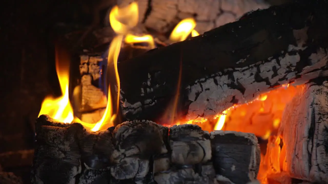 Close up view of campfire of Aspen made of logs burning focusing on the coals with yellow flames stationary shot with no movement