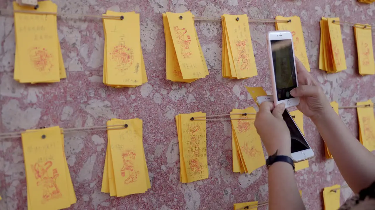 Female taking photograph of prayer joss paper in Confucius temple in Taiwan