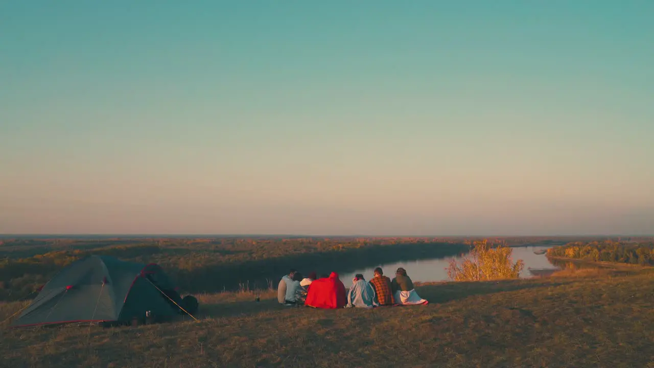 young tourists group spends time at burning bonfire by river