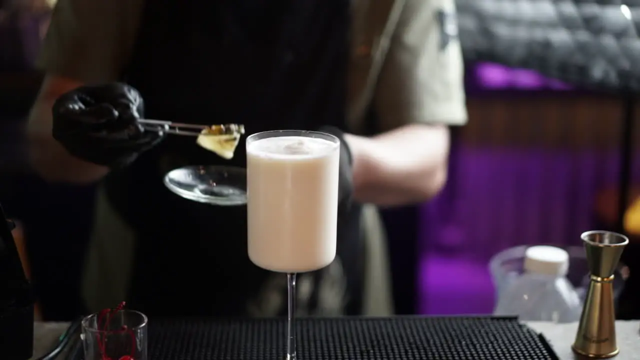 latin bartender decorating piña colada garnishing cherry slow motion