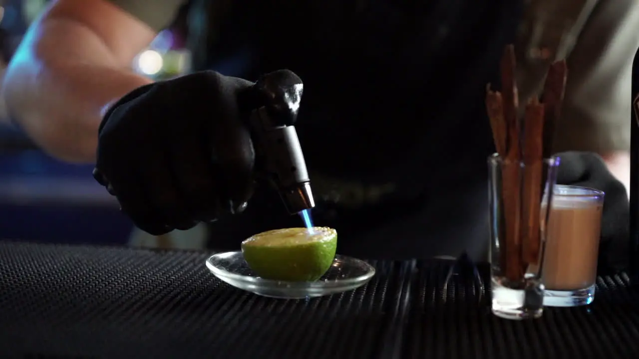 bartender flaming torching torch lemon for cocktail garnish slow motion