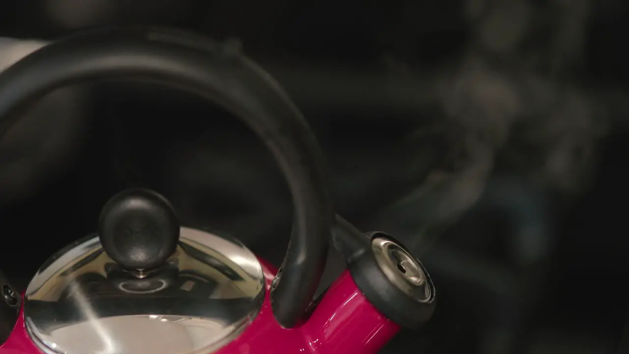 Close up of a red tea pot bursting with steam indicated the water is boiling