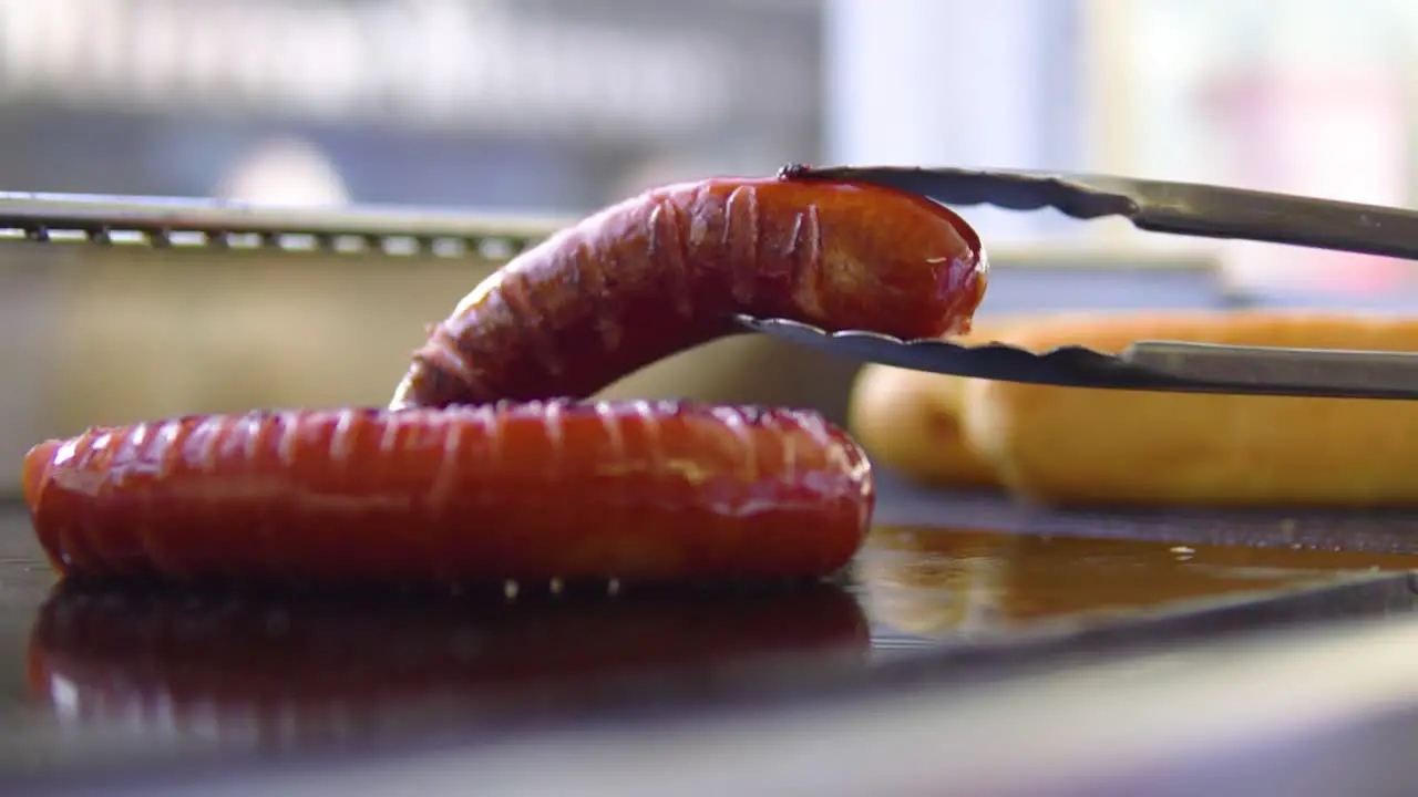 Turning sausage around on outdoor grill at high street in slowmotion