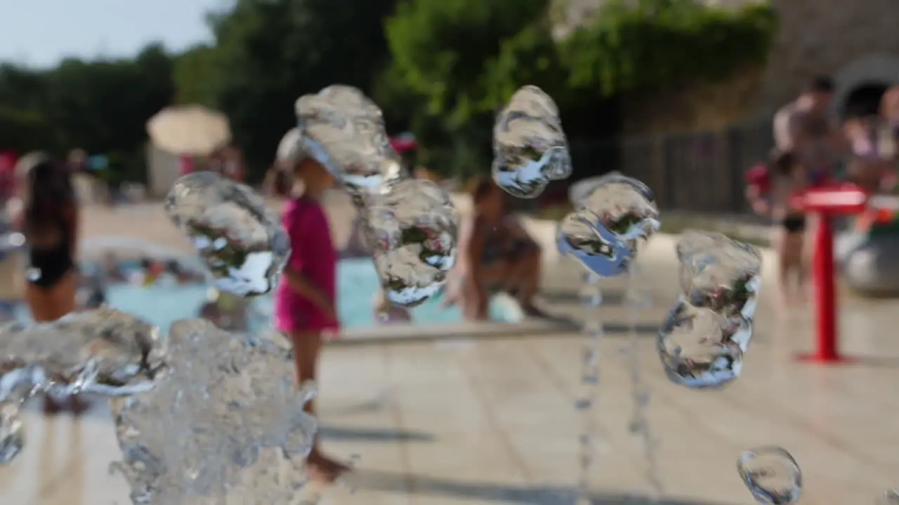 Water fountain in slow motion camping people chilling in a pool background