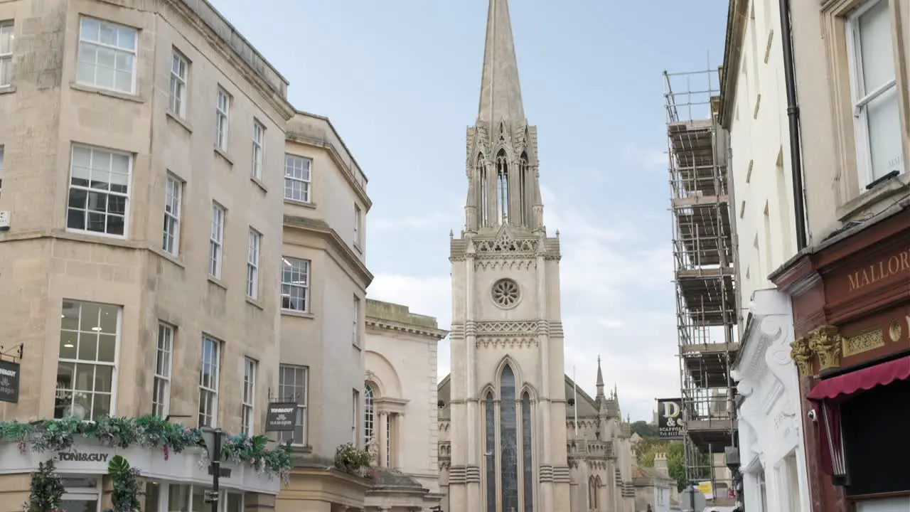 Several people walk along a busy corner with a Church in the background