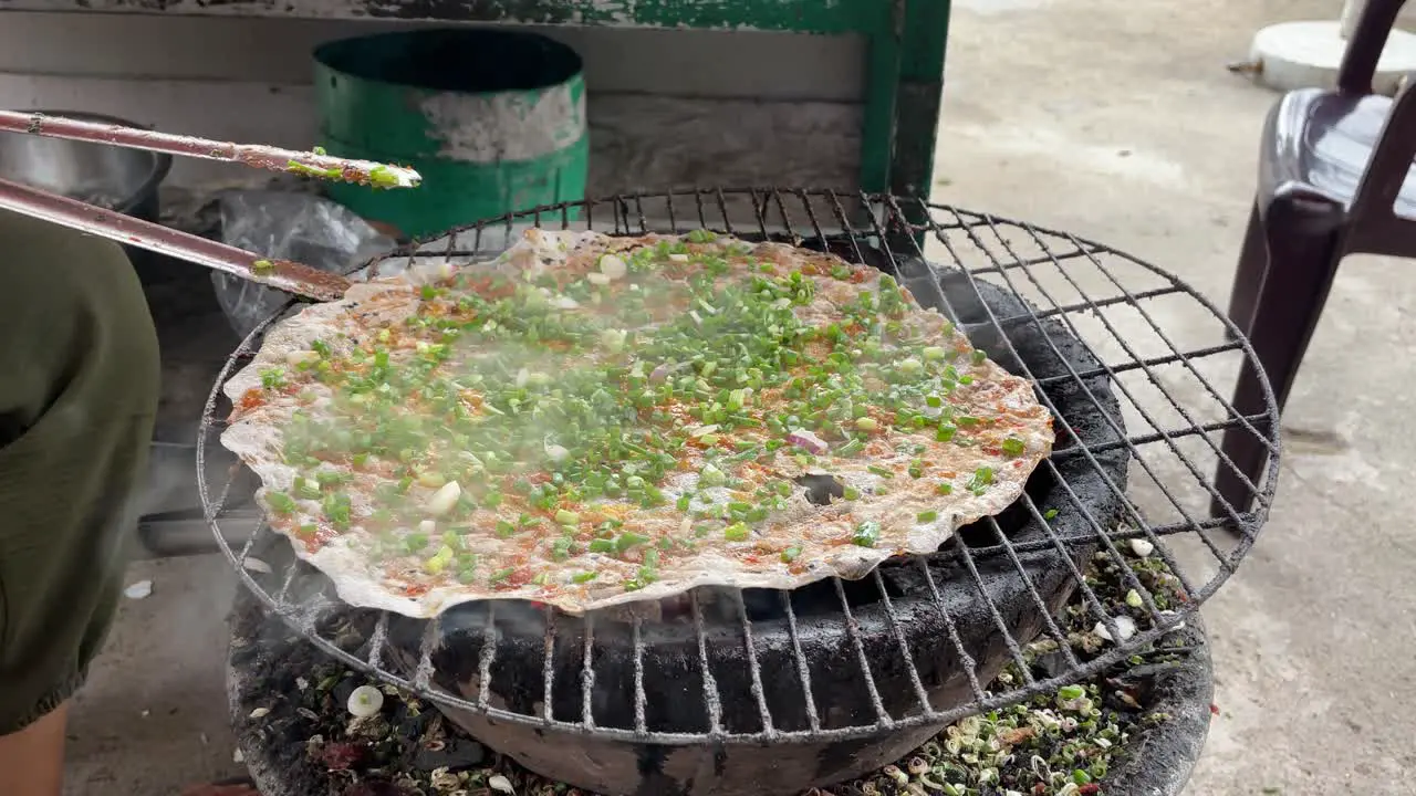 Person is grilling rice paper one of the favorites in Asian cousin also being called pizza Dalat” street street food concept