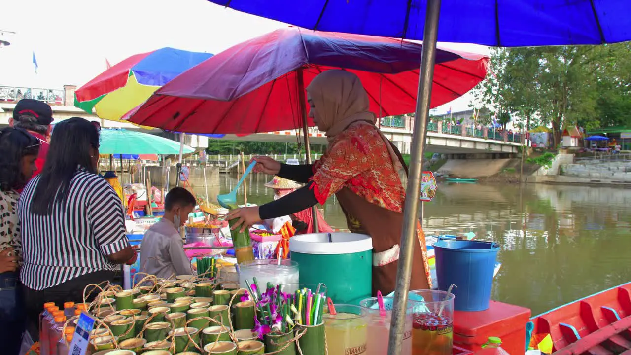 Muslim young woman selling juices in cartons at a Thailand's floating market