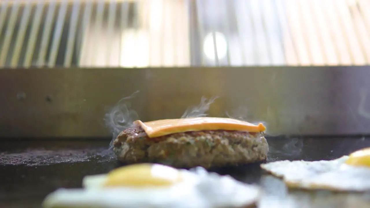 Person with white protective gloves putting cheese on a grilled burger at fast food