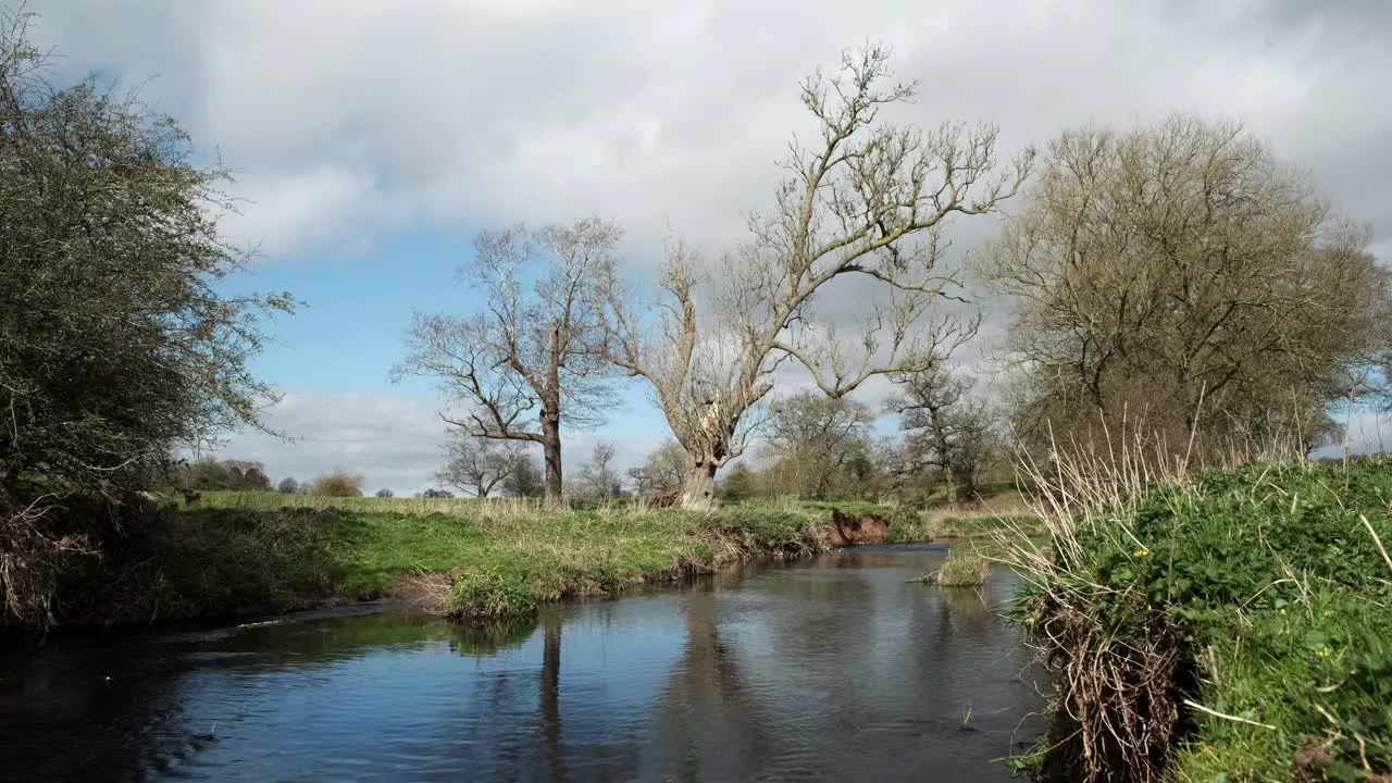 A sunny windy day on the river Arrow in Warwickshire England as clouds roll over head