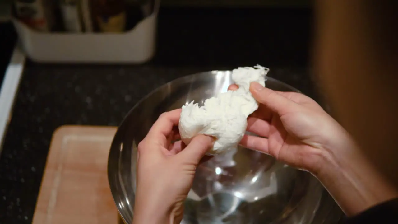 A woman chef tearing mozzarella ball to smaller pieces