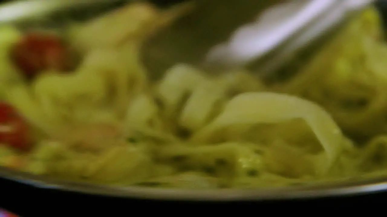 Chef stirring white sauce seafood pasta with shrimp and tomatoes with tong