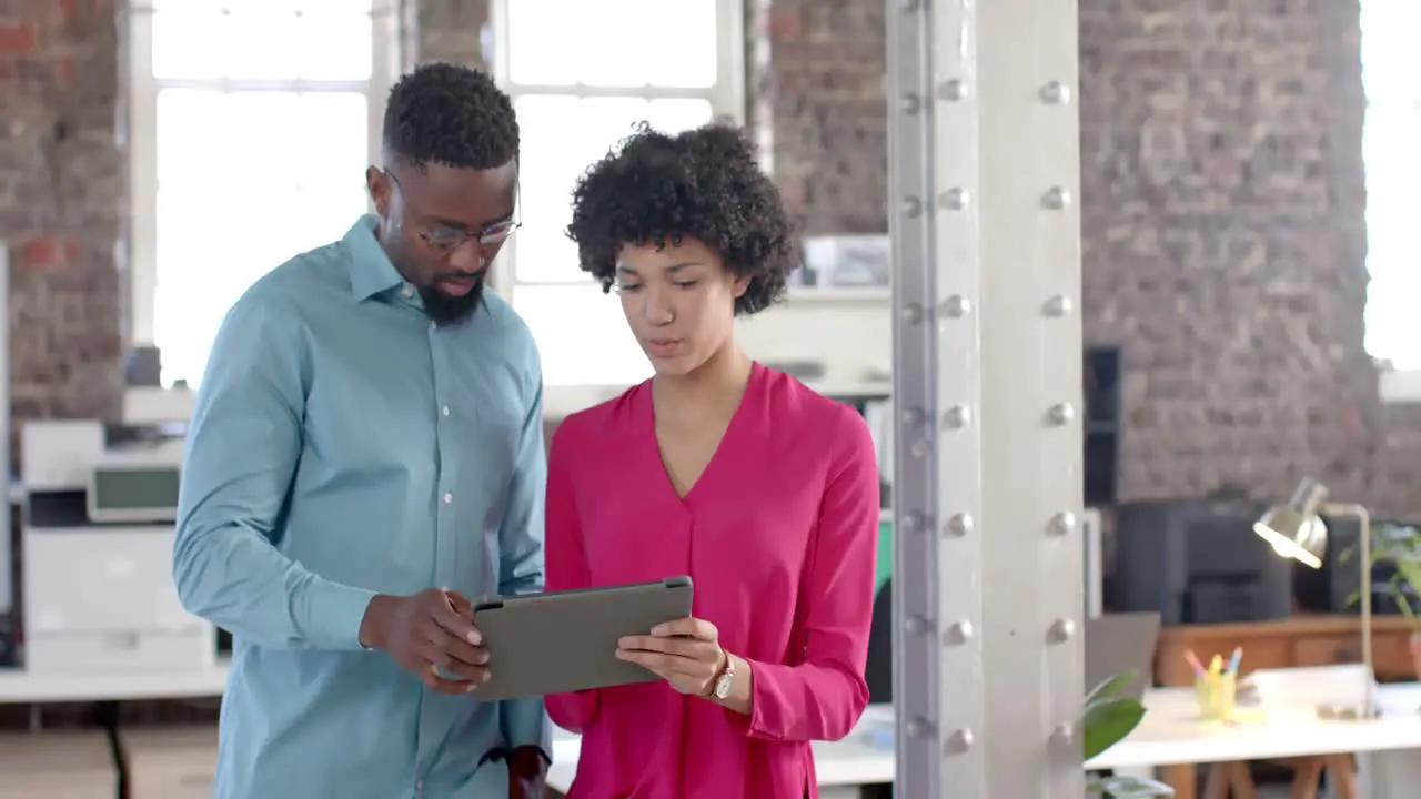 Happy diverse colleagues talking and using tablet in office in slow motion