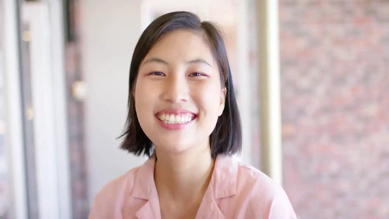 Portrait of smiling casual asian businesswoman in office in slow motion