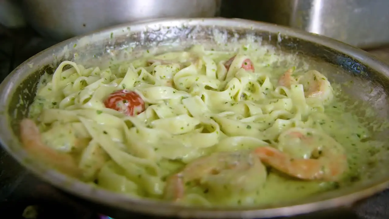 Slow orbit closeup of white sauce seafood pasta in frying pan