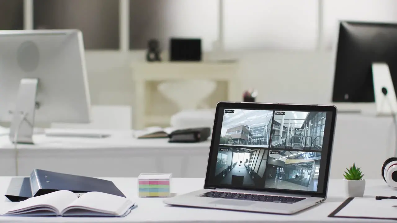 Laptop on office desk showing four security camera views of office complex slow motion